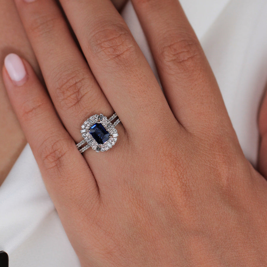 Anillo de oro blanco de 18k con zafiro central, orla de diamantes y diamantes en los laterales