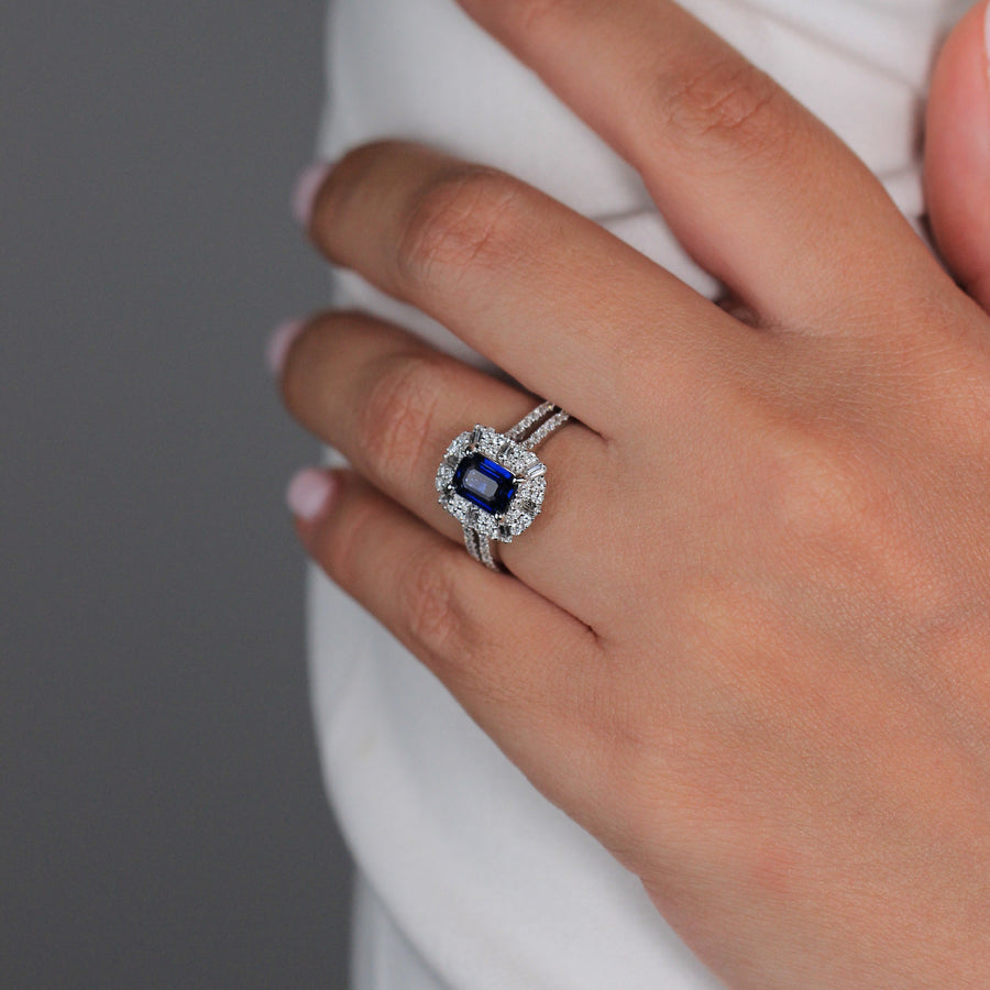 Anillo de oro blanco de 18k con zafiro central, orla de diamantes y diamantes en los laterales