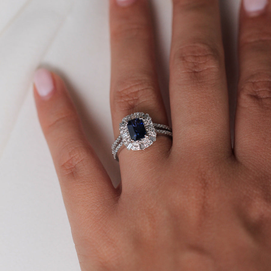 Anillo de oro blanco de 18k con zafiro central, orla de diamantes y diamantes en los laterales