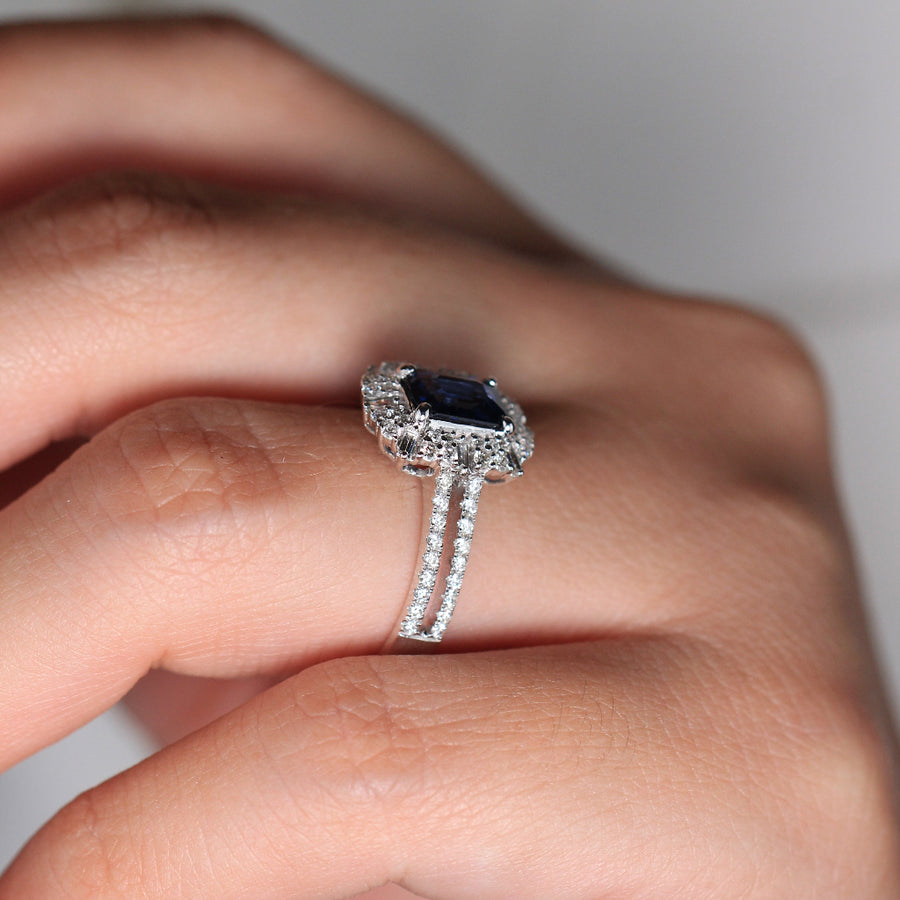 Anillo de oro blanco de 18k con zafiro central, orla de diamantes y diamantes en los laterales